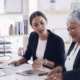 two businesswomen at a table looking at papers